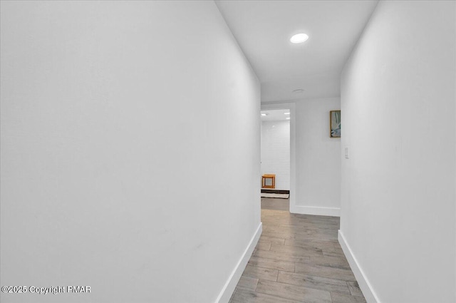 corridor with light wood-type flooring and baseboards