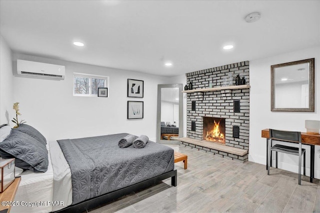 bedroom with baseboards, a wall unit AC, wood finished floors, a brick fireplace, and recessed lighting