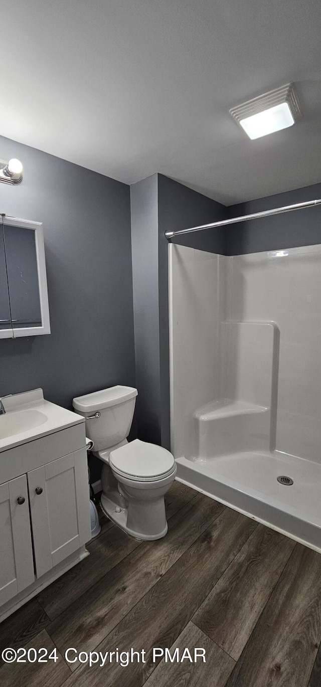 bathroom featuring vanity, a stall shower, wood finished floors, and toilet