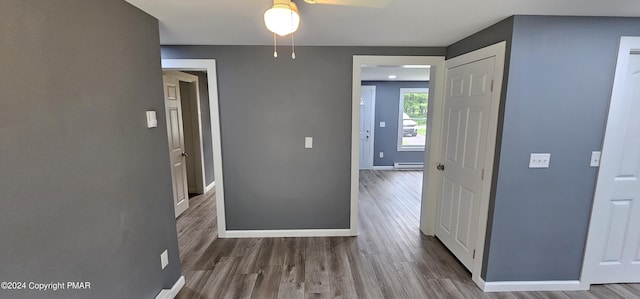 corridor with wood finished floors, baseboards, and a baseboard radiator