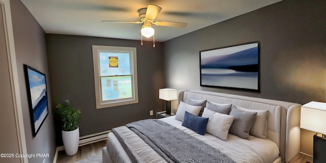 bedroom with ceiling fan, baseboard heating, and wood finished floors