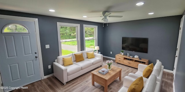 living room with baseboards, light wood-style floors, and a ceiling fan