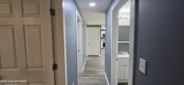 hallway with light wood finished floors and a sink