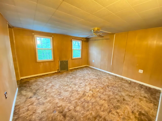 carpeted empty room with radiator heating unit, a ceiling fan, and baseboards