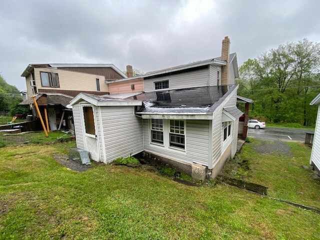 rear view of house featuring a yard and a chimney