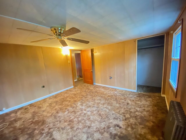 unfurnished bedroom with radiator heating unit, carpet flooring, ceiling fan, and baseboards