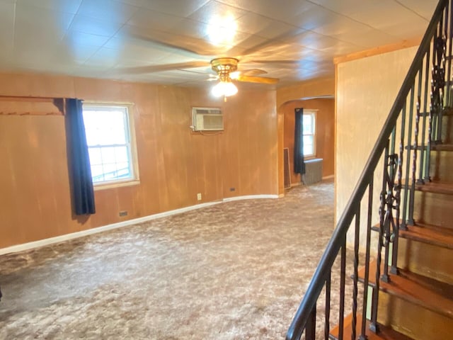 below grade area with a wall mounted air conditioner, carpet flooring, ceiling fan, and healthy amount of natural light