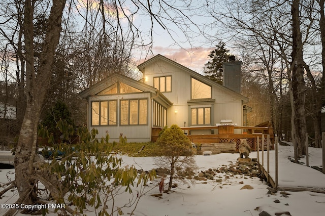 snow covered property featuring a deck and a chimney