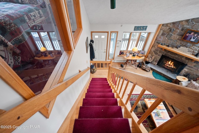 staircase with a fireplace and a textured ceiling