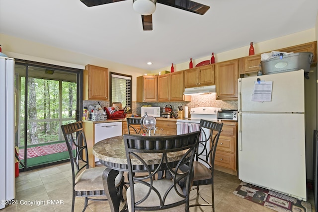 kitchen with under cabinet range hood, backsplash, white appliances, and a ceiling fan