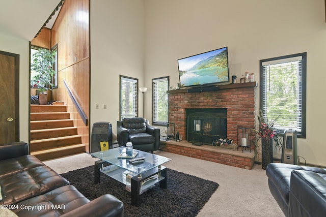 living area featuring stairway, carpet flooring, a fireplace, and a towering ceiling