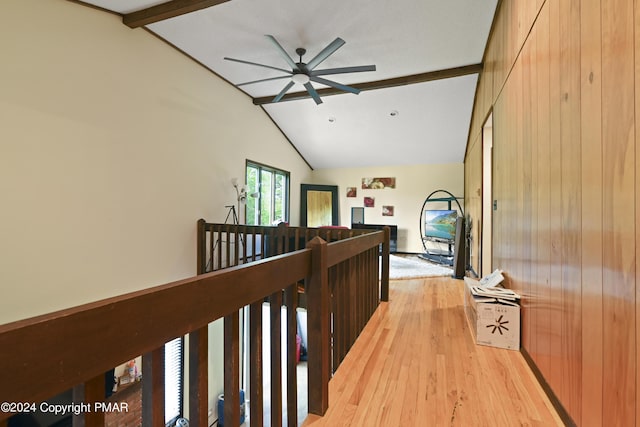 hall with an upstairs landing, lofted ceiling with beams, and light wood-style floors