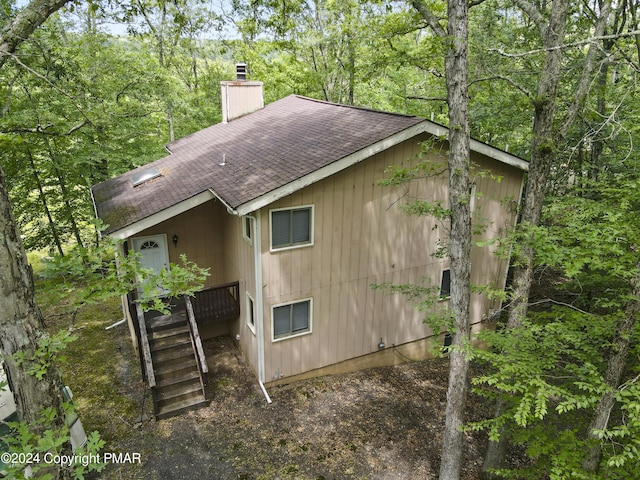 view of property exterior featuring a chimney and a shingled roof