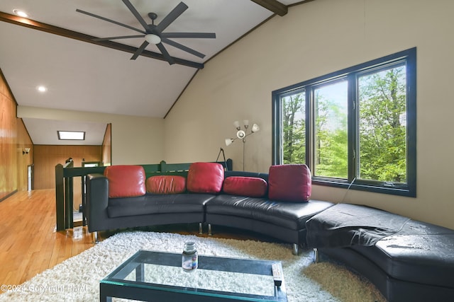 living area featuring lofted ceiling with beams, light wood-style floors, and a ceiling fan