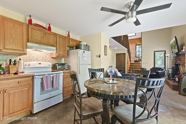 kitchen featuring a ceiling fan, under cabinet range hood, backsplash, white appliances, and light countertops