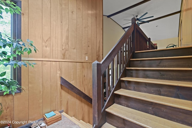 stairs with ceiling fan and wood walls