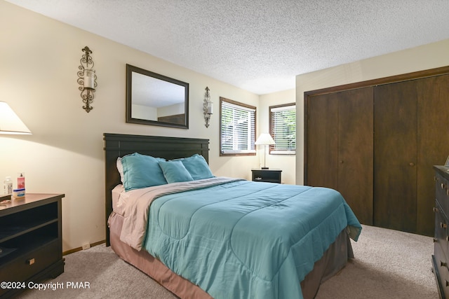 bedroom with a textured ceiling, baseboards, a closet, and light carpet