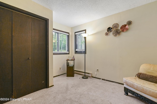 living area with a baseboard heating unit, a textured ceiling, baseboards, and light carpet