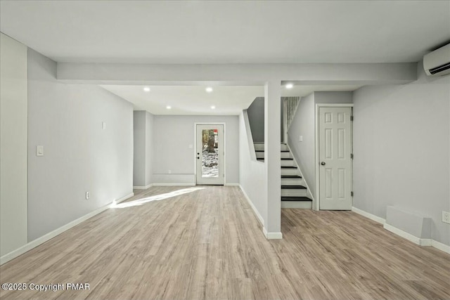 basement featuring a wall mounted air conditioner and light hardwood / wood-style flooring