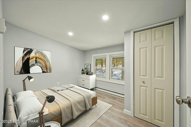 bedroom featuring baseboard heating, a closet, and light hardwood / wood-style flooring