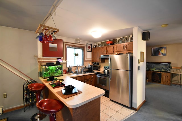 158 Saunders Dr, Bushkill, PA 18324 - kitchen featuring appliances with stainless steel finishes, a peninsula, light countertops, a sink, and under cabinet range hood