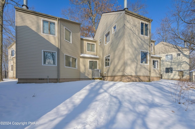 snow covered back of property with cooling unit and crawl space