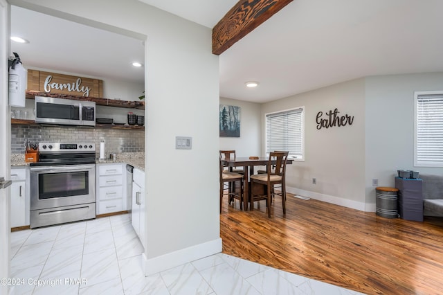 kitchen featuring white cabinets, marble finish floor, appliances with stainless steel finishes, backsplash, and open shelves