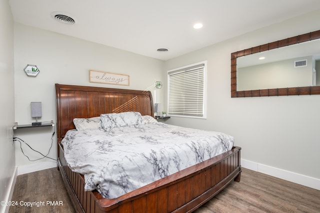 bedroom with wood finished floors, visible vents, and baseboards