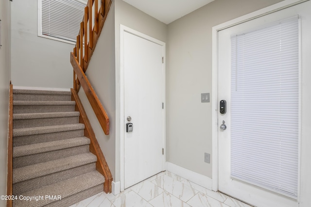 doorway with stairs, marble finish floor, and baseboards