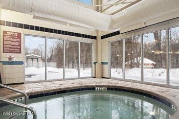 snow covered pool with an indoor hot tub