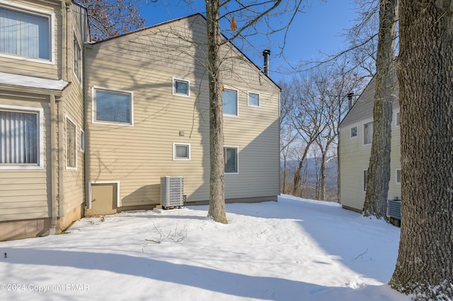 snow covered back of property featuring central AC