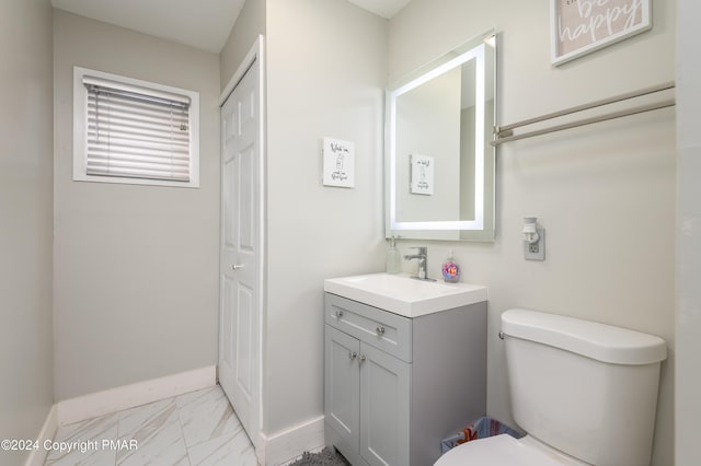 bathroom with toilet, marble finish floor, vanity, and baseboards