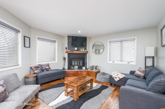 living room featuring a large fireplace, wood finished floors, and recessed lighting