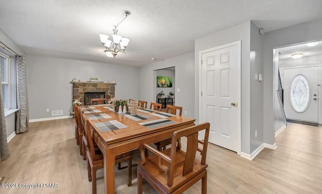 dining space with visible vents, a fireplace, light wood-style flooring, and an inviting chandelier