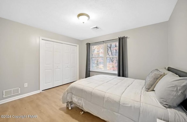 bedroom with baseboards, a closet, visible vents, and wood finished floors