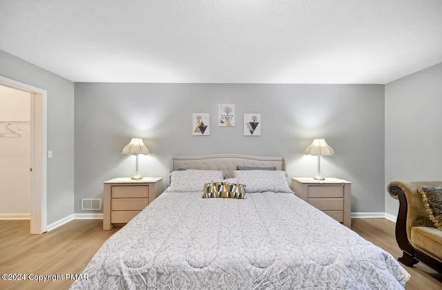 bedroom with visible vents, baseboards, and wood finished floors