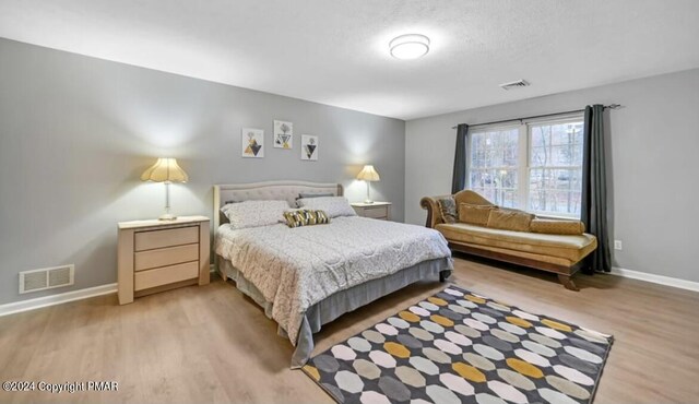 bedroom featuring light wood-type flooring, visible vents, and baseboards