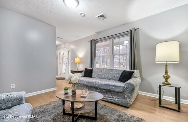 living room featuring visible vents, baseboards, and wood finished floors