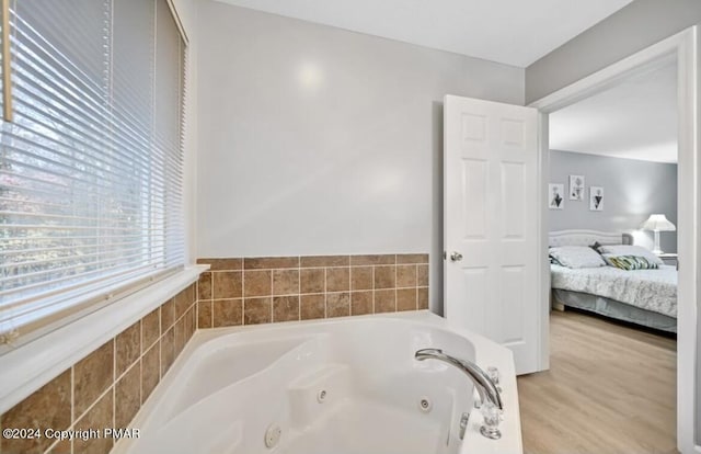 ensuite bathroom with wood finished floors, a whirlpool tub, and ensuite bathroom