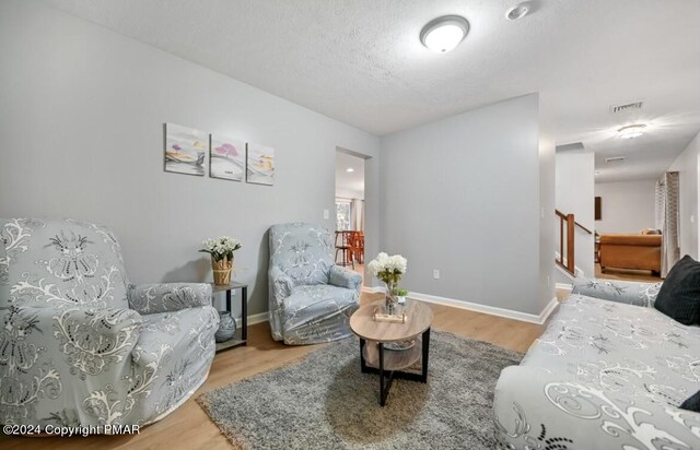 living area featuring a textured ceiling, baseboards, and wood finished floors