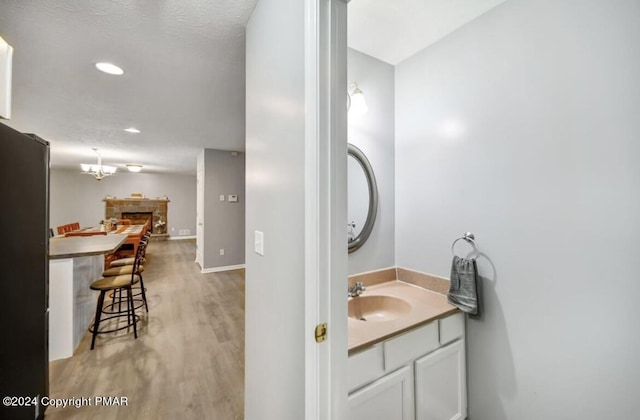 bathroom featuring recessed lighting, a fireplace, wood finished floors, vanity, and baseboards