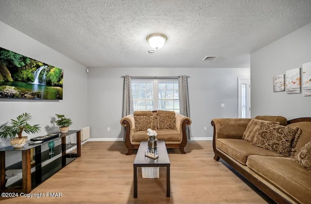 living area featuring light wood-type flooring, visible vents, and baseboards