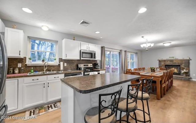 kitchen featuring visible vents, decorative backsplash, dark countertops, appliances with stainless steel finishes, and a sink