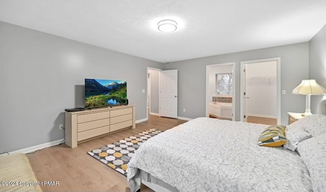 bedroom featuring a spacious closet, wood finished floors, and baseboards