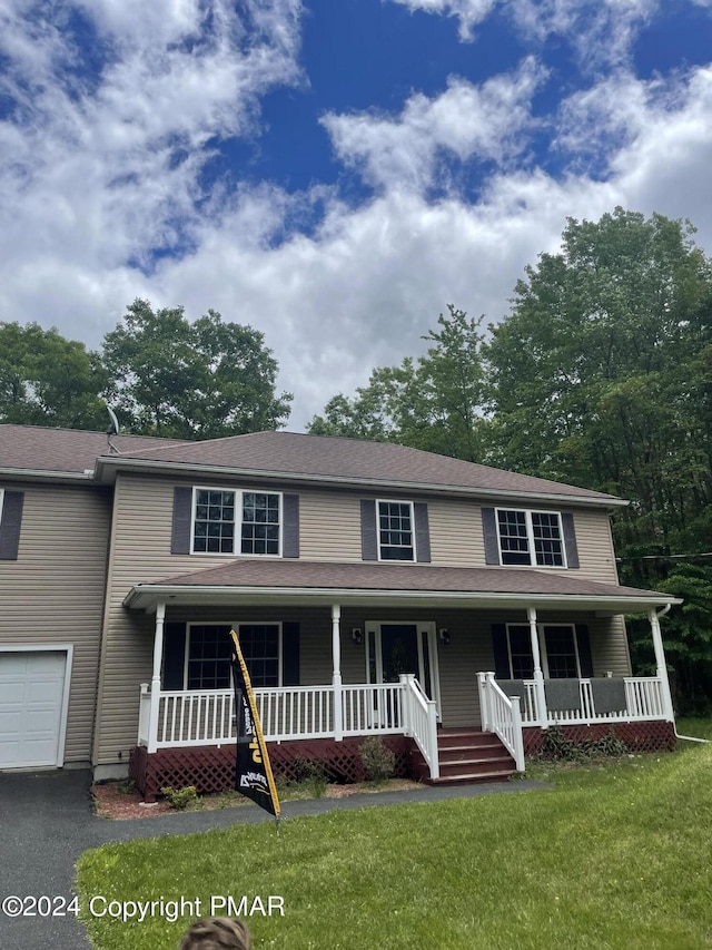 view of front of home featuring aphalt driveway, a front lawn, and a porch