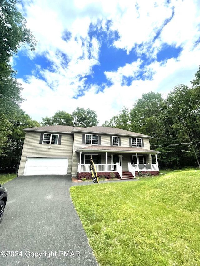 view of front facade featuring driveway, a porch, a front lawn, and an attached garage