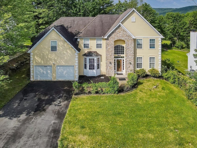 2358 Snapdragon Pt, East Stroudsburg, PA 18301 - traditional home with asphalt driveway, stucco siding, stone siding, a front yard, and an attached garage