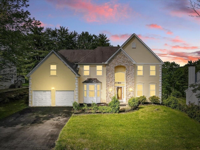 2358 Snapdragon Pt, East Stroudsburg, PA 18301 - traditional home with stucco siding, asphalt driveway, stone siding, a lawn, and a garage