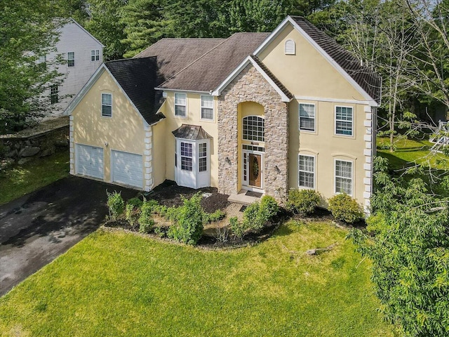 2358 Snapdragon Pt, East Stroudsburg, PA 18301 - traditional-style house with stucco siding, stone siding, asphalt driveway, a front lawn, and roof with shingles