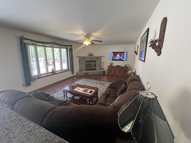 living area featuring wood finished floors, ceiling fan, and a fireplace